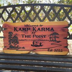 a wooden sign that says welcome to kempp karma at the point on a park bench