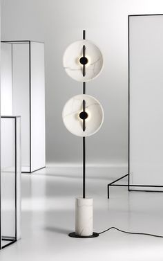 three lamps are on the floor in an empty room, one is white and the other is black