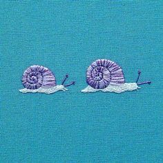 two purple snails are in the middle of blue water with one snail on it's back