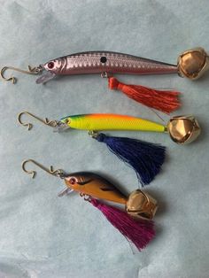 five different types of fishing lures on a white surface with gold hooks and tassels