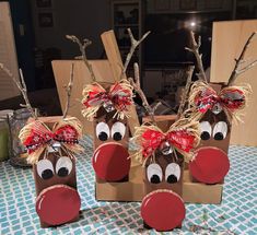 three paper bags with reindeer noses and bows on them sitting on a blue checkered table cloth