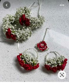 three pieces of red and white flowers are arranged on a counter top with earrings, necklace and earring