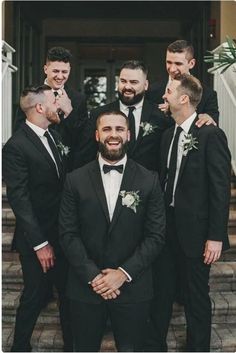 a group of men standing next to each other wearing suits and bow ties on their heads