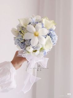 a woman holding a bouquet of white and blue flowers