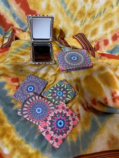 an open box sitting on top of a tie dye blanket next to two small coasters