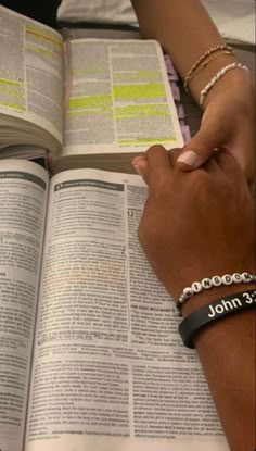 two people holding hands over an open book with the words john 3 16 on it