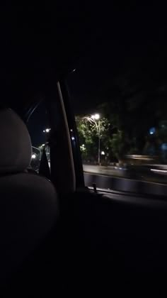 the interior of a car at night with street lights and trees in the back ground