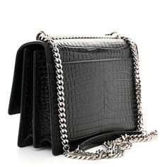 This is an authentic SAINT LAURENT Calfskin Crocodile Embossed Medium Monogram Sunset in Black. This shoulder bag is crafted of crocodile-embossed calfskin leather in glossy black. The bag features a polished gold chain-link shoulder strap with a leather shoulder pad, a front-facing flap with a signature gold YSL logo, gusseted sides and an exterior rear patch pocket. The bag opens with a magnetic snap to a black suede partitioned interior with a patch pocket. Ysl Logo, Emboss, Shoulder Pads, Black Suede, Chain Link, Patch Pocket, Gold Chains, Calf Skin, Silver Chain