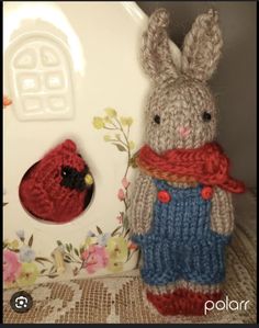 a knitted stuffed animal next to a small red bird