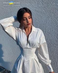 a woman in a white dress is posing for the camera with her hands on her head