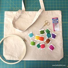 a tote bag with scissors and thread spools laid out next to it