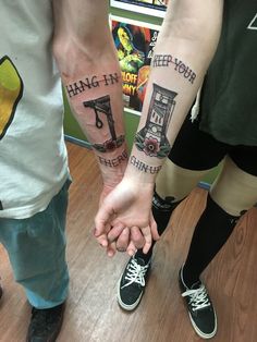 two people holding hands with tattoos on their arms