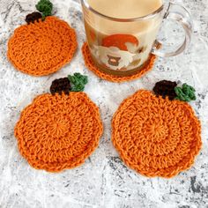 three crocheted pumpkin coasters next to a cup of coffee