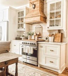 a kitchen with white cabinets and an oven in the center is filled with utensils