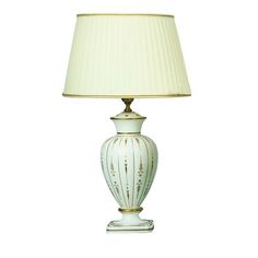 a white lamp with a beige shade on top of it and a gold trim around the base