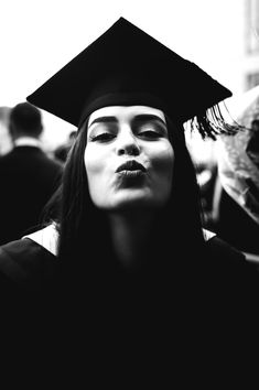 a woman wearing a graduation cap and gown with her eyes closed in front of the camera