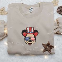 America Mickey Embroidered Shirt, Disney Embroidered Shirt, Best Patriotic Shirts Welcome to Tinicloset, your ultimate destination for custom embroidered shirts and a wide range of embroidered sweatshirts, T-shirts, and hoodies that will leave you feeling both patriotic and fashion-forward. At Tinicloset, we take pride in delivering top-notch quality products that are not only stylish but also a true testament to American spirit and creativity. Our collection is a celebration of the red, white, Disney Style Embroidered Cotton Tops, Disney Cotton Tops With Embroidered Graphics, Disney Cotton Top With Embroidered Logo, Disney Embroidered Cotton Tops, Disney Embroidered Crew Neck Tops, Disney Multicolor Mickey Mouse T-shirt, Mickey Mouse Cotton T-shirt With Crew Neck, Summer Mickey Mouse Cotton T-shirt, Mickey Mouse Silhouette