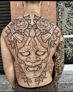 the back of a man's body with tattoos on it and roses growing out of his head