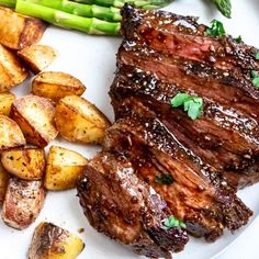 steak, potatoes and asparagus on a white plate with green garnish