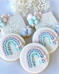 three decorated cookies sitting next to each other on top of a white table with blue and pink decorations