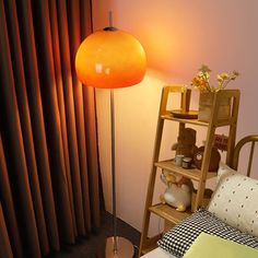 an orange floor lamp next to a bed in a room with curtains and a teddy bear