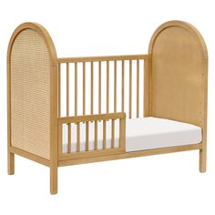 a wooden crib with a white mattress on it's side and an arched headboard