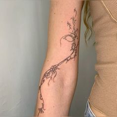 a woman's arm with a vine tattoo on the left side of her arm