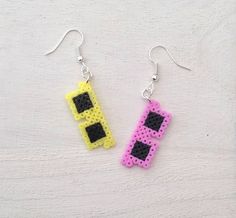 pair of earrings made out of legos on white surface with black and yellow squares