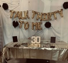 a table that has some balloons on it and the words talk about to me spelled in gold