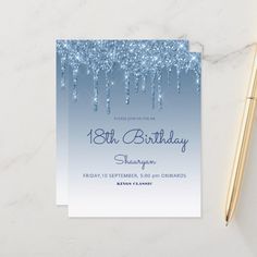 a blue and white birthday party card with icicles on the front, next to a pen