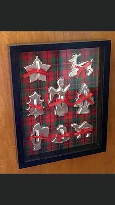 a shadow box with christmas decorations made out of cookie cutters and ribbon tied around the edges