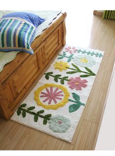 a white rug with flowers and leaves on the floor next to a wooden bed frame