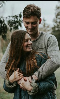 a man and woman hugging each other in the grass