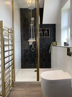 a bathroom with a toilet, shower and black tiled walls on the wall next to it