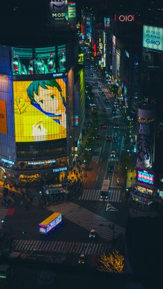 an aerial view of a busy city street at night with billboards on the buildings