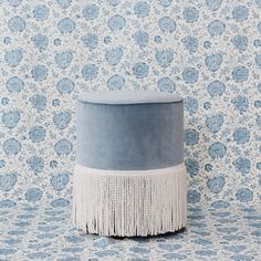 a blue and white ottoman sitting on top of a floor next to a wallpaper