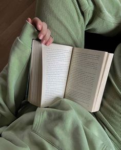 a person is holding an open book in their lap