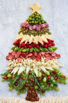 a christmas tree made out of grapes, meats and nuts on a marble surface