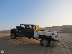 a truck is driving through the desert with sand dunes in the backgrouds