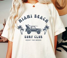 Miami Beach Surf Club Beach Tee Shirt Unisex Florida Tshirt Gift The Comfort Colors C1717 100% Ring Spun Cotton T-Shirt is very appropriately-named. All colors are inspired by nature and have a perfect lived-in, weathered look. Shirts are sent through a unique dyeing process that makes them incredibly soft and long-lasting. Each piece is soft-washed 50 times before making its way to you! Stitched at the collar, armhole, sleeves and bottom hem for ultimate durability, you will notice the density and quality of this shirt, but won't mind living in it. COMFORT COLORS 1717 ADULT TEE 6.1 Oz/SqYd 100% Ring Spun Cotton Soft-washed garment-dyed fabric Double-needle collar Twill taped neck and shoulders Twill label Relaxed fit Double needle armhole, sleeve and bottom hems Tubular body PROPER SIZING Casual Surfing Camp Shirt With Graphic Print, Casual Graphic Print Camp Shirt For Surfing, White Tropical Camp Shirt With Graphic Print, White Crew Neck Camp Shirt For Beach, Casual Surfing T-shirt With Custom Print, Graphic Print Crew Neck Camp Shirt For Vacation, Tropical Graphic T-shirt For Summer Adventures, White Tropical T-shirt With Letter Print, Tropical Graphic Print T-shirt For Summer Adventures