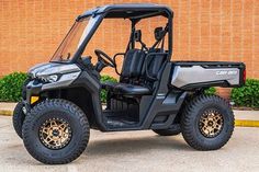 a black utility vehicle parked in front of a brick building with its doors open and the seat up