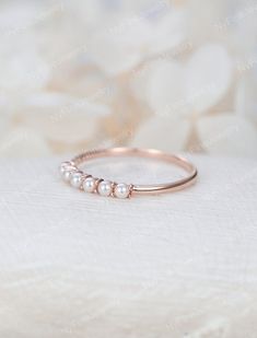 a gold ring with three pearls on the side, sitting on top of a white cloth