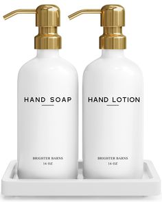 two bottles of hand lotion sitting on a white tray with gold faucets