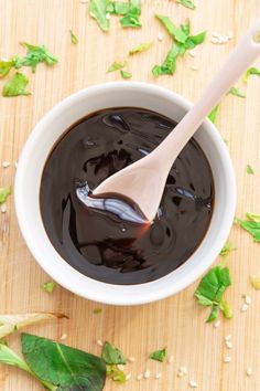 a wooden spoon in a bowl filled with chocolate sauce and green leaves on the table