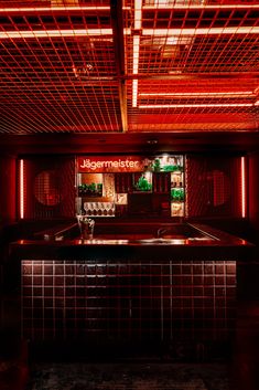 a dimly lit bar with red lights and tiled counter tops in the middle of it