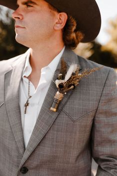 a man in a suit and hat with a feather boutonniere on his lapel