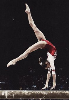 a man doing a handstand on top of a beam