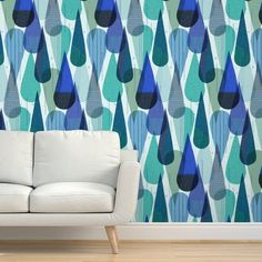 a white couch sitting in front of a wall with blue and green drops on it