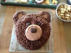 a cake shaped like a bear with chocolate icing and nuts in front of it