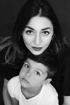 a black and white photo of a woman with her head on the shoulders of a young boy